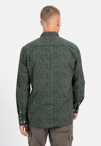 Grøn mønstret skjorte med lange ærmer og knap-ned krave, der har en stiplet tekstur og knapmanchetter. Enkelt design på ryggen.