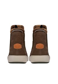 Botas de tobillo de cuero marrón con un acabado texturizado, cuentan con un talón reforzado, una etiqueta de logo de cuero beige y una suela de goma ligera.