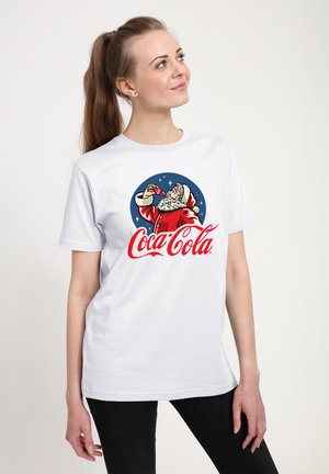 Biała koszulka z krótkim rękawem, ozdobiona grafiką Świętego Mikołaja pijącego Coca-Colę, z czerwonymi i niebieskimi akcentami. Gładki materiał, luźny krój.