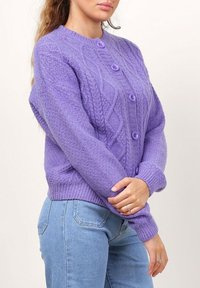 Cardigan en tricot violet avec un motif en câble texturé et des poignets côtelés. Doté de quatre boutons assortis et d'une coupe décontractée.