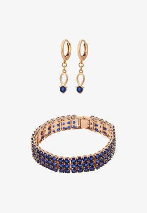 Boucles d'oreilles dorées avec des accents de pierres bleues, présentant un design en boucle. Accompagnées d'un bracelet assorti, orné de pierres bleues disposées en motif lié.