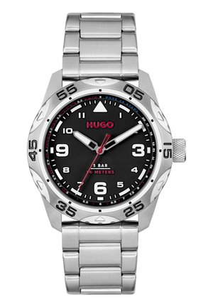 Silver stainless steel watch with a black dial. Features bold white hour markers, red accents, and a textured crown for adjustments.