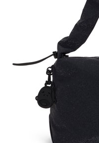 Sac en tissu noir avec un motif texturé, comprenant un tirette de fermeture éclair avec un pendentif en forme de singe noir et une poignée rembourrée.