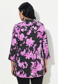 Tunika a maniche lunghe in tessuto nero con un motivo floreale rosa e a griglia. Il design presenta un collo rotondo e una vestibilità comoda.