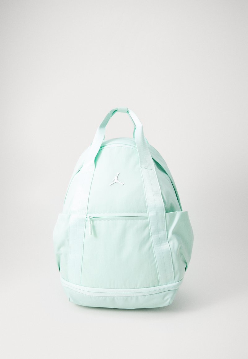 Mochila verde menta con forma redondeada, que cuenta con un bolsillo delantero con cremallera, bolsillos laterales y un logo blanco. Fabricada con tejido duradero.