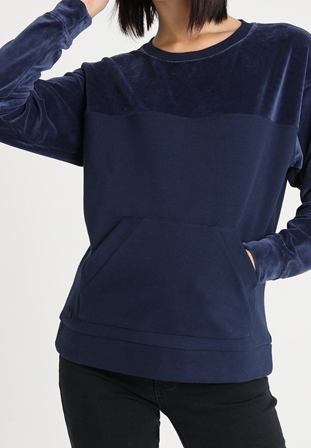 Mörkblå sweatshirt med en sammetslen överpanel och framficka. Långa ärmar, rundad halsringning och mjuk textur. Avslappnad passform.