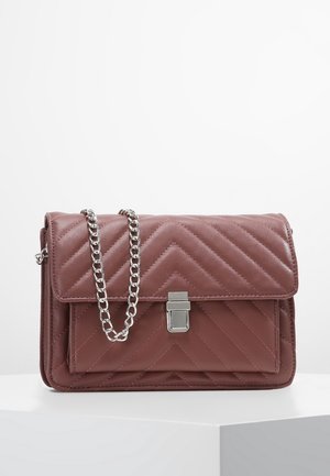 Mauve doorgestikte leren crossbodytas met chevronstiksels, voorvak, zilveren sluiting en een dikke zilveren kettingriem op een witte ondergrond.