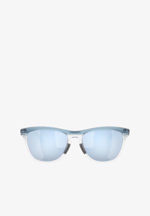 Occhiali da sole tinti di blu con montatura trasparente, forma a occhio di gatto e lenti specchiate. Hardware minimo e superficie liscia.