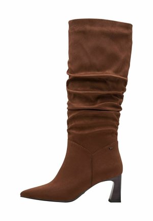 Bruine slouchy kniehoog laars van zacht suede. Kenmerkt zich door een spitse neus en een stevige hak, met een gladde textuur en minimale hardware.