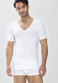 T-shirt ajusté blanc à col V, à manches courtes, texture douce et finition lisse. Porté avec un boxer blanc assorti.