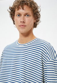 Stribet sweater lavet af bomuld; har vandrette blå og hvide striber, rund halsudskæring og en afslappet pasform. Blød tekstur med korte ærmer.