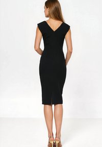 Czarna dopasowana sukienka z krótkimi rękawkami, dekoltem w kształcie litery V z tyłu oraz długością do kolan. Posiada zamek z tyłu i rozcięcie na dole dla swobody ruchów.