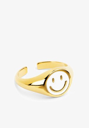 Anillo de pulsera de oro con diseño de cara sonriente blanca elevada, acabado suave y extremos abiertos para un tamaño ajustable.