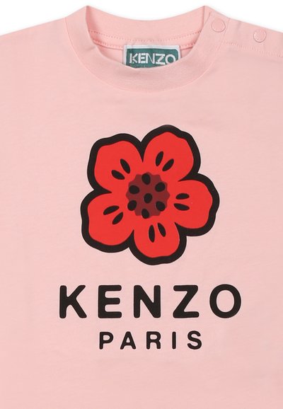 T-shirt en coton rose clair avec un grand motif de fleur rouge et un lettrage noir « KENZO PARIS » en dessous. Boutons-pression à l'épaule.