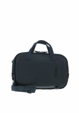 Sac de transport Thule compact de couleur gris foncé avec double poignées, poche avant et bandoulière réglable.