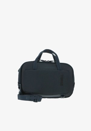 Sac de transport Thule compact de couleur gris foncé avec double poignées, poche avant et bandoulière réglable.