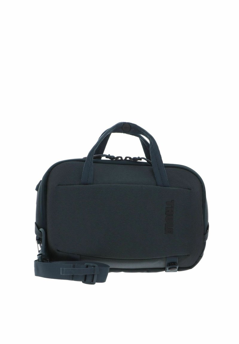 Sac de transport Thule compact de couleur gris foncé avec double poignées, poche avant et bandoulière réglable.