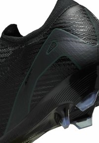 Zwarte sportieve schoen met een gestructureerde synthetische bovenkant, slank ontwerp, ribbelkraag en doorzichtige kunststof noppen op de buitenzool.