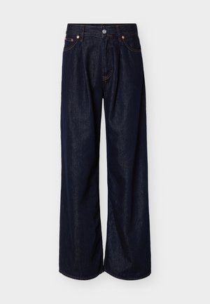 Donkere blauwe jeans met wijde pijpen, voorzien van knopen aan de voorkant en een vijfzakkenontwerp, op een effen lichte achtergrond.