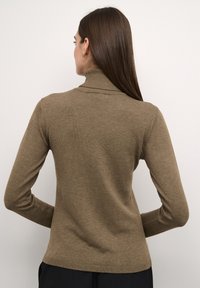 Barna, bordázott garbós pulóver hosszú ujjal, testhez simuló fazonban és sima textúrával. Nincsenek figyelemfelkeltő minták vagy díszítések.