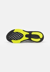Sole di scarpa sportiva nera e giallo neon con un motivo a rete texture. Presenta una forma liscia e sagomata e un materiale in gomma resistente.