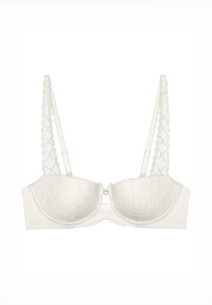Soutien-gorge en dentelle blanche avec des bonnets structurés, présentant un motif floral, des bords festonnés et des bretelles décoratives avec un accent en forme de cœur au centre.