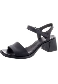 Sandale en cuir noir avec un bout ouvert, une bride à la cheville et un talon bloc. Texture lisse et design minimaliste avec un semelle légèrement incurvée.