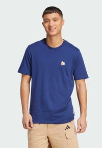 Navy blå bomulds t-shirt, korte ærmer, rund halsudskæringer, med et lille hvidt og gult grafisk motiv på venstre bryst, glat tekstur.