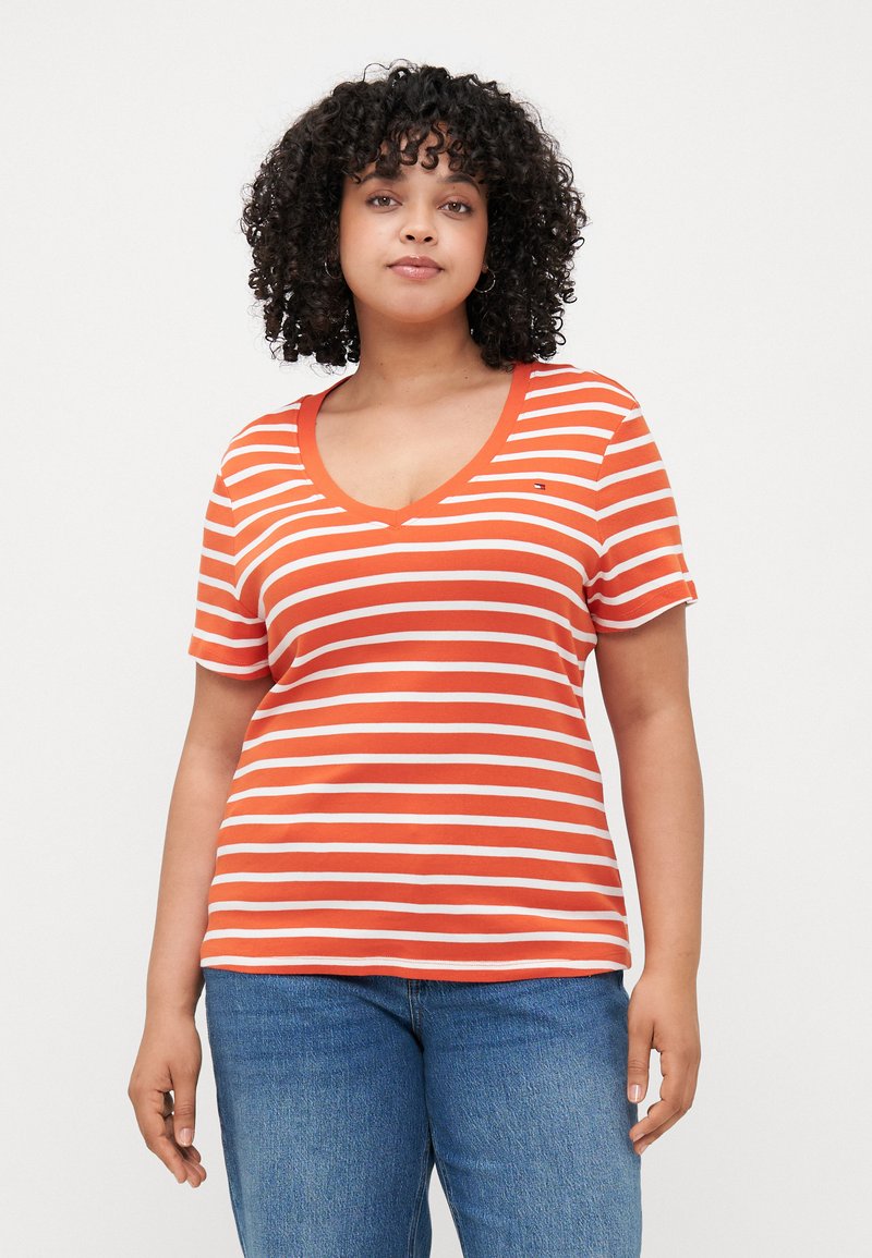 Red and white striped T-shirt with a V-neck and short sleeves, made of soft fabric. Featuring a small logo detail on the chest.