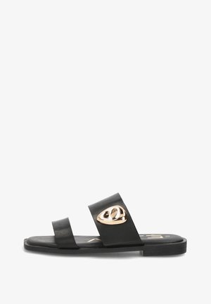 Sandalia plana negra con dos tiras, la delantera lisa y la del medio con un emblema abstracto dorado.