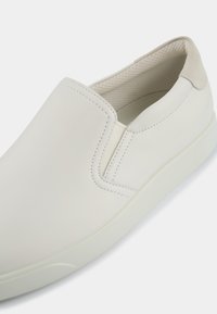 Weiße Slipper mit einem glatten Lederoberteil, runder Zehenpartie und beige Wildlederspitze. Das Innere verfügt über ein strukturiertes Mesh-Futter.