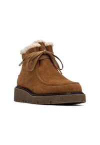 Botas de tobillo de ante marrón con un suave cuello de crema, diseño de cordones y suela gruesa texturizada. Presenta detalles cosidos en la parte superior.