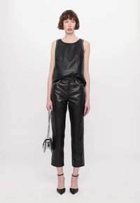 Black leather sleeveless top with studded detailing at the shoulders, paired with high-waisted black leather pants with side accents.