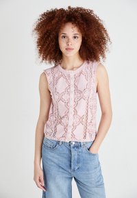Top sans manches rose avec de délicates dentelles, encolure ronde et fermeture à boutons. Associé à un jean en denim bleu clair.