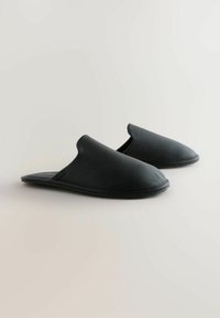 Black slip-on slippers made of textured leather with a rounded toe and flexible rubber sole. Smooth interior lining. No visible hardware.
