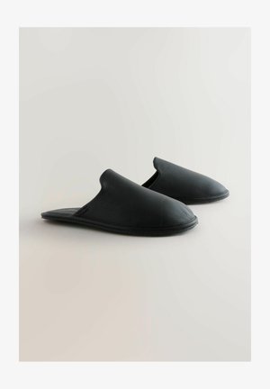 Melnas slīdošās čības, izgatavotas no teksturētas ādas ar noapaļotu purngalu un elastīgu gumijas zoli. Gluda iekšpuses oderējums. Nav redzamu aksesuāru.