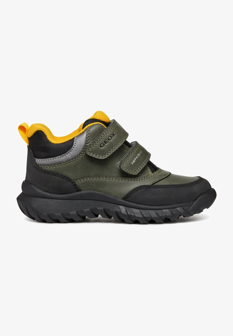 Scarpa sportiva verde e nera con cinturini in Velcro, suola in gomma testurizzata e un accento giallo sul collo. Realizzata in materiali sintetici.