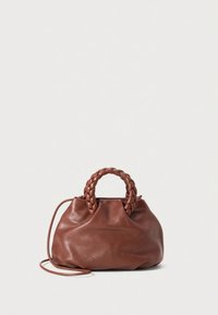 Brūna ādas soma ar pinumiem rokturiem un garu plānu siksnu, mīksta un nedaudz noslīdējusi, uz vienkārša gaiša fona.