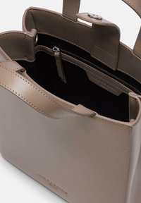 Be�żowa skórzana torebka, gładka faktura, usztywniony kształt, górne uchwyty, kieszeń na zamek, minimalne okucia, czarne wnętrze, detal z logo po boku.