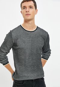 Maglione in bianco e nero con texture, colletto rotondo, rifinitura a contrasto e maniche lunghe, caratterizzato da un sottile motivo a griglia.