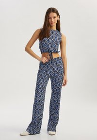 Conjunto de dos piezas azul con estampado, que incluye un top corto con lazos y pantalones de pierna ancha, ambos confeccionados con tejido ligero.
