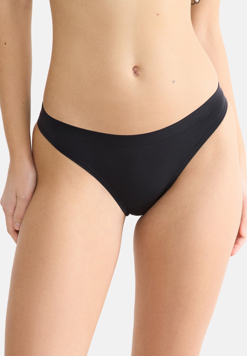 Zwarte bikini onderkant gemaakt van gladde stof. Heeft een low-rise snit, minimale bedekking en een naadloze tailleband voor comfort.