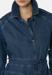 Denim jack met een donkerblauwe kleur, hoge kraag, knoopsluiting en een strikceintuur. Voorzien van gedetailleerde stiksels en klassieke ontwerpelementen.