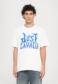 White cotton t-shirt featuring a blue graphic text design. Short sleeves and a round neckline. Relaxed fit with a casual appearance.