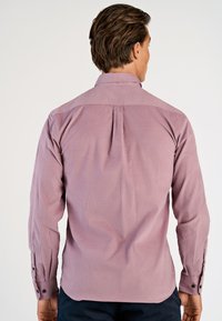 Camicia a maniche lunghe di un leggero colore malva, realizzata in un tessuto texturizzato. Presenta un colletto standard, una piega sul retro e polsini con bottoni scuri.