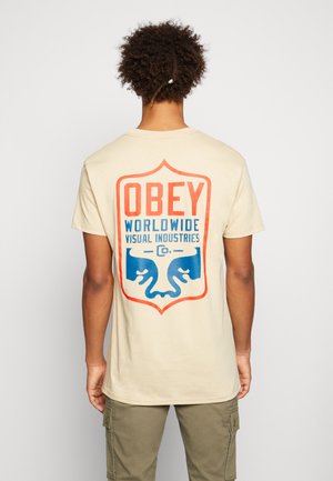 VISUAL BADGE - Print T-shirt - sand
