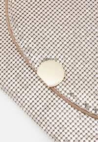 Pochette en mesh métallique avec un fermoir en doré circulaire. Comprend une bordure en tissu taupe lisse et un motif en grille.