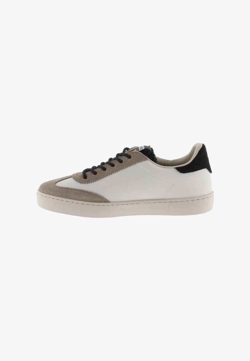 Zapatilla de corte bajo hecha de cuero blanco con acentos de ante beige. Cuenta con cordones negros y un talón texturizado en negro. Suela de goma, diseño minimalista.