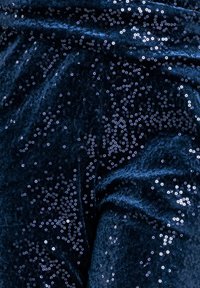 Tessuto blu navy con paillettes, caratterizzato da una superficie liscia e da paillettes circolari lucide distribuite in modo casuale che creano una superficie riflettente.