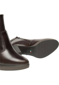 Stivaletti in pelle marrone con zip laterale, punta curva e tacco basso. La suola in gomma testurizzata presenta un battistrada modellato per una migliore aderenza.